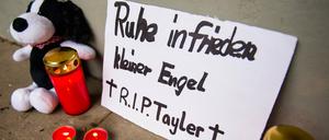 Ein Schild mit der Aufschrift "Ruhe infrieden kleiner Engel. R.I.P. Tayler", Kerzen und ein Plüschtier stehen in Hamburg.