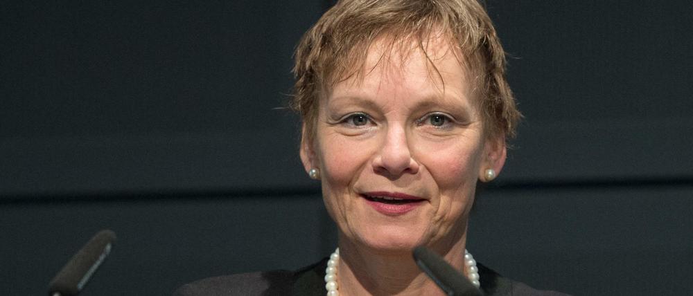 Eine Frau steht an einem Rednerpult vor zwei Mikrofonen.