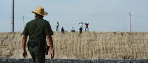 Grenzfälle: Hier, auf US-Seite, der Mann von der Border Patrol, dort, auf mexikanischer Seite, über dem Rio-Grande-Flussbett, die illegalen Grenzquerer, in der Nähe von McAlley, Texas