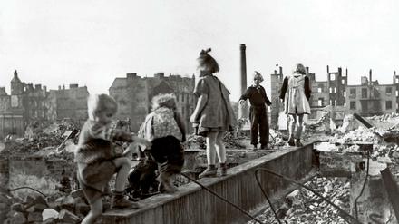 Eine Gruppe Kinder spielt in den Trümmern einer zerstörten Stadt im Deutschland der Nachkriegszeit.