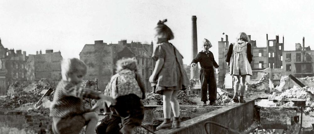 Eine Gruppe Kinder spielt in den Trümmern einer zerstörten Stadt im Deutschland der Nachkriegszeit.