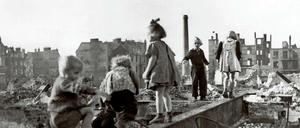 Eine Gruppe Kinder spielt in den Trümmern einer zerstörten Stadt im Deutschland der Nachkriegszeit. 