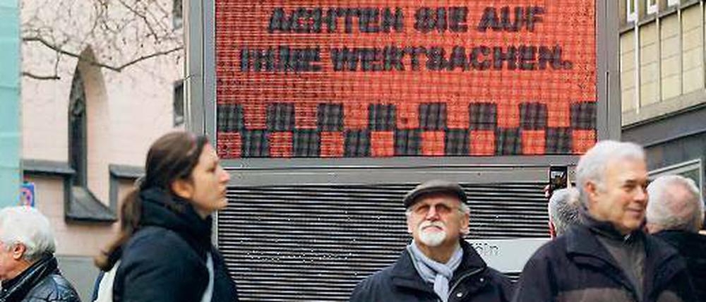 Ein Plakat weist in der Kölner Innenstadt Passanten auf die Gefahr durch Taschendiebe hin.