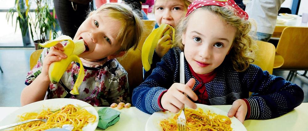 Schülerinnen essen Spaghetti in der Schulmensa.