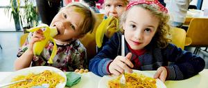 Schülerinnen essen Spaghetti in der Schulmensa.