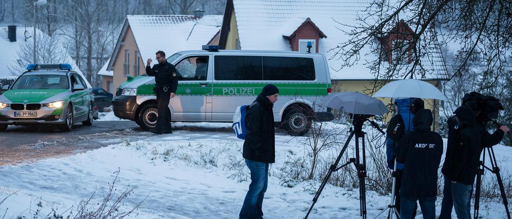 Medienvertreter stehen vor zwei Polizeifahrzeugen am 04.01.2015 in Oberaurach (Bayern) in der Nähe des Ortes, an dem in der Silvesternacht ein 11-jähriges Mädchen durch einen Kopfschuss getötet worden war.