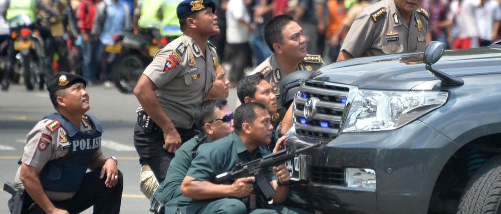 Polizisten suchen Schutz hinter einem Fahrzeug in der indonesischen Hauptstadt Jakarta.