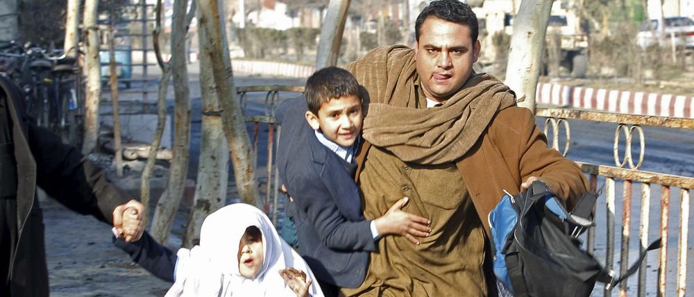 Ein Mann bringt nach einer Explosion vor dem pakistanischen Konsulat in Dschalalabad seine Familie in Sicherheit.