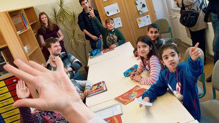 Kinder sitzen in einem Klassenraum vor Schulbüchern.