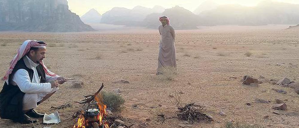 Kaffee zum Sonnenaufgang. Frühmorgens haben diese beiden Beduinen im Wadi Rum ein Feuer angezündet. Von hier starten Kameltouren.