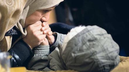 Eiszeit. Eine Mutter wärmt in einem Zelt vor dem Lageso die Hände ihres Kindes. Trotz der Kälte stehen hier täglich hunderte Menschen für Unterstützungsleistungen an.