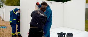 Mitarbeiter des technischen Hilfswerks (THW) bauen in der Flüchtlingsnotunterkunft Scheuen bei Celle neue Schnellbauhütten auf. 