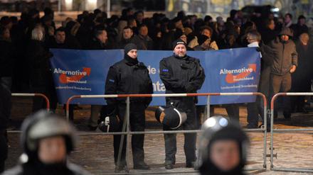 Teilnehmer einer Kundgebung der AfD stehen hinter einer Polizeiabsperrung vor dem Landtag in Potsdam (Brandenburg). 