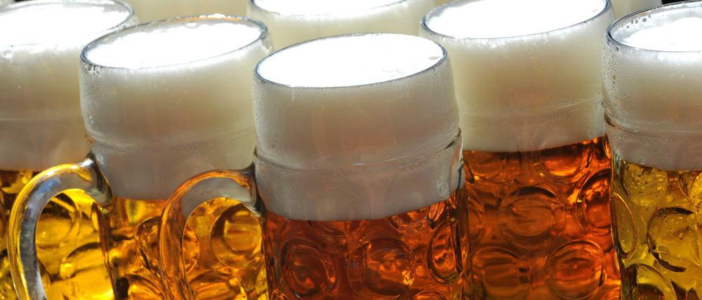 Maßkrüge stehen auf der Schänke in einem Biergarten auf dem Oktoberfest in München.