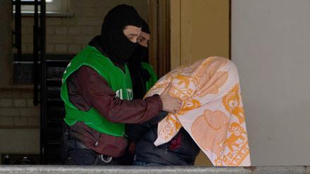 Polizisten führen bei einer Razzia gegen Islamisten am 04.02.2016 in Berlin einen mit einem Tuch verdeckten Verdächtigen ab. Alle Verdächtigen stammen aus Algerien.