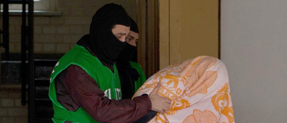 Polizisten führen bei einer Razzia gegen Islamisten am 04.02.2016 in Berlin einen mit einem Tuch verdeckten Verdächtigen ab. Alle Verdächtigen stammen aus Algerien.