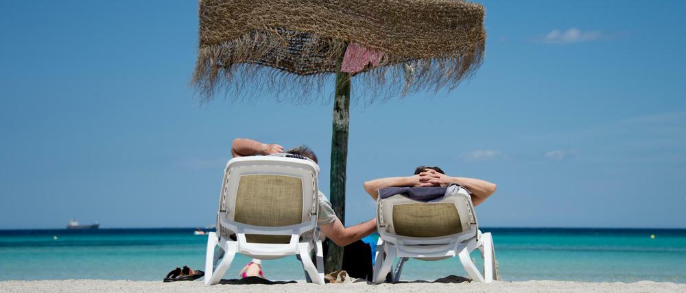 Ab nach Malle. Deutsche Urlauber am Strand an der Plaja de Muro im Norden der Mittelmeerinsel Mallorca.