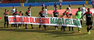 Amedspor-Spieler mit Aufruf. Auf dem Plakat steht: "Lasst Kinder nicht sterben, lasst sie zum Spiel kommen" vor dem Hinspiel im Viertelfinale des türkischen Pokals gegen Fenerbahce. 