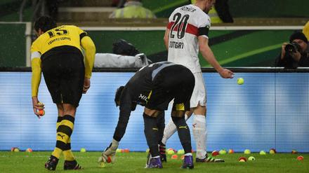 Fußball DFB-Pokal Viertelfinale: VfB Stuttgart - Borussia Dortmund am 09.02.2016 in der Mercedes-Benz-Arena in Stuttgart (Baden-Württemberg). Stuttgarts Christan Gentner (hinten), Dortmunds Mats Hummels (r) und Dortmunder Torwart Roman Bürki sammeln Tennisbälle vom Spielfeld, die von Dortmunder Fans auf den Platz geworfen wurden. Foto: Marijan Murat/dpa (Wichtiger Hinweis: Der DFB untersagt die Verwendung von Sequenzbildern im Internet und in Online-Medien während des Spiels (einschließlich Halbzeit). Sperrfrist! Der DFB erlaubt die Publikation und Weiterverwertung der Bilder auf mobilfunkfähigen Endgeräten (insbesondere MMS) und über DVB-H und DMB erst nach Spielende.) +++(c) dpa - Bildfunk+++