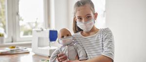 Ein Mädchen und ihre Puppe mit handgenähten Masken.