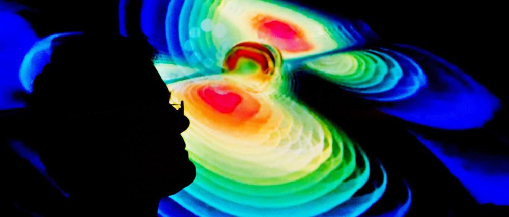 Der Schattenriss eines Mannes ist vor der Visualisierung der Gravitationswellen zu sehen.