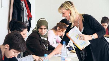 Eine Lehrerin spricht in einer Schulklasse mit jungen Erwachsenen.