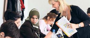 Eine Lehrerin spricht in einer Schulklasse mit jungen Erwachsenen.