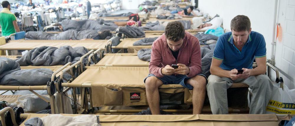 Smartphones sind für Flüchtlinge oft unverzichtbar. Hier chatten die syrischen Flüchtlinge Ammar (l.) und Walid in einer Notunterkunft in der Hanns-Martin-Schleyerhalle in Stuttgart mit ihren Familien.