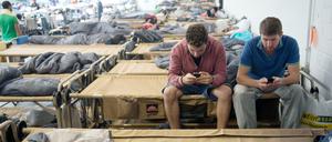 Smartphones sind für Flüchtlinge oft unverzichtbar. Hier chatten die syrischen Flüchtlinge Ammar (l.) und Walid in einer Notunterkunft in der Hanns-Martin-Schleyerhalle in Stuttgart mit ihren Familien. 