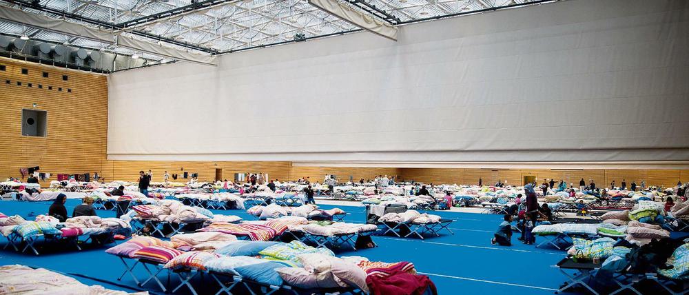 Voll, eng, provisorisch. Auch in einer Halle am Olympiapark sind Flüchtlinge untergebracht. Und so schnell wird sie wohl nicht geräumt werden.