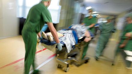 Ein Ärzteteam schiebt einen Patienten auf einer Krankentrage durch einen Raum.