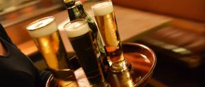 Eine Bedienung trägt in einem Lokal ein Tablett mit Bier. 