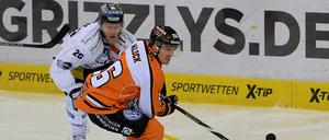 Wolfsburgs Tyson Mulock (r) und Berlins Florian Busch kämpfen um den Puck. 