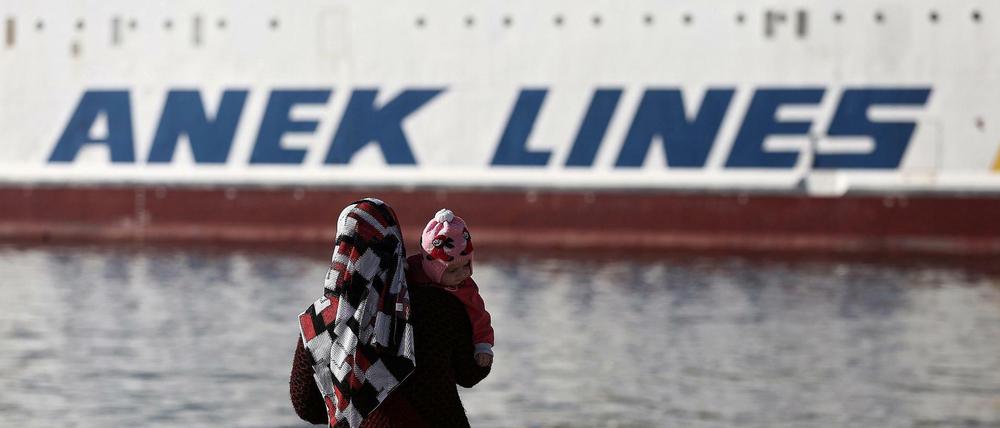 Eine geflüchtete syrische Frau blickt im Hafen von Piräus auf eine Fähre. Der Transport von Flüchtlingen soll nach dem Willen der griechischen Regierung vorerst eingeschränkt werden.