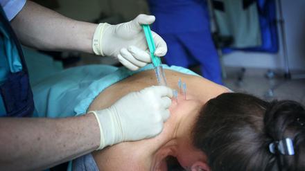Mit Nadeln und Spritze. Bei vielen Schmerzpatienten ist die Behandlung nicht optimal, kritisieren Experten. 