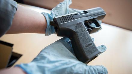 Eine Mitarbeiterin des Bundeskriminalamtes hält am Montag in Wiesbaden eine Pistole in ihren Händen. Bei einer großen Razzia gegen Betreiber und Nutzer illegaler Plattformen im Internet sind neun Verdächtige festgenommen und zahlreiche Beweismittel sichergestellt worden.