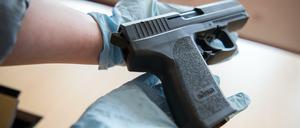 Eine Mitarbeiterin des Bundeskriminalamtes hält am Montag in Wiesbaden eine Pistole in ihren Händen. Bei einer großen Razzia gegen Betreiber und Nutzer illegaler Plattformen im Internet sind neun Verdächtige festgenommen und zahlreiche Beweismittel sichergestellt worden.