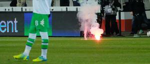 Wolfsburer Fans werfen Feuerwerk auf das Spielfeld.