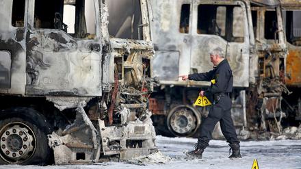 Ein Polizist sichert Spuren an mehreren ausgebrannten Lkw der Bundeswehr am Dienstag in Leipzig. Unbekannte Brandstifter haben auf dem Werkstattgelände acht Lastwagen und zwei Anhänger angezündet - sechs dieser Fahrzeuge gehören der Bundeswehr.