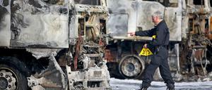 Ein Polizist sichert Spuren an mehreren ausgebrannten Lkw der Bundeswehr am Dienstag in Leipzig. Unbekannte Brandstifter haben auf dem Werkstattgelände acht Lastwagen und zwei Anhänger angezündet - sechs dieser Fahrzeuge gehören der Bundeswehr.