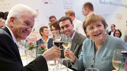 Baden-Württembergs Ministerpräsident Winfried Kretschmann (Die Grünen), sein Finanzminister Nils Schmid (SPD) und Bundeskanzlerin Angela Merkel (CDU.) stoßen beim Sommerfest des Landes Baden-Württemberg in Berlin mit Wein an.  