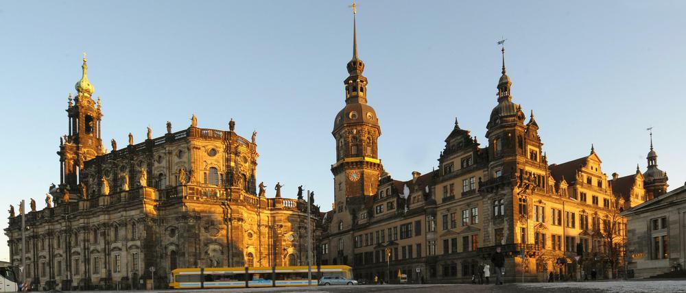 Angestrahlt von der tiefstehenden Abendsonne spiegelt sich das Ensemble des Dresdner Residenzschlosses in einer vereisten Pfütze auf dem Theaterplatz in Dresden. 