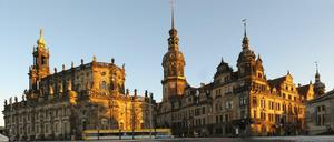 Angestrahlt von der tiefstehenden Abendsonne spiegelt sich das Ensemble des Dresdner Residenzschlosses in einer vereisten Pfütze auf dem Theaterplatz in Dresden.