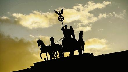 Nur als Silhouette ist in Berlin die Quadriga im Licht der untergehenden Sonne zu erkennen. 