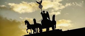 Nur als Silhouette ist in Berlin die Quadriga im Licht der untergehenden Sonne zu erkennen. 