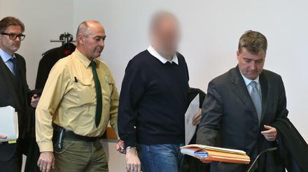 Ein wegen des Missbrauchs von rund 20 Jungen angeklagter Kinderarzt wird am 23.11.2015 im Strafjustizzentrum Augsburg (Bayern) zwischen seinen Anwälten Ralf Schönauer (r) und Moritz Bode (l) in einen Gerichtssaal geführt. Der Mann wurde am Donnerstag zu mehr als 13 Jahren Haft verurteilt. 