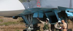Russische Soldaten überprüfen einen SU-34-Bomber auf dem syrischen Stützpunkt Hmeimim. Von dort aus haben die ersten Kampfflieger am Dienstag das Land in Richtung Russland verlassen.