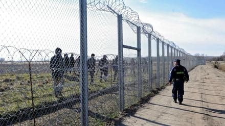 Geschlossen. Ein ungarischer Polizist beobachtet Flüchtlinge auf der anderen Seite des Zauns auf serbischem Territorium. 