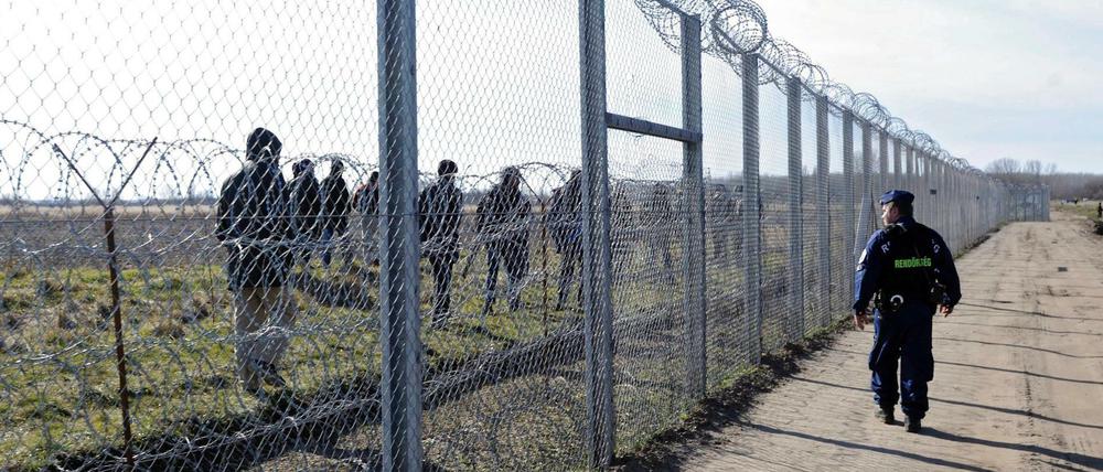Geschlossen. Ein ungarischer Polizist beobachtet Flüchtlinge auf der anderen Seite des Zauns auf serbischem Territorium. 