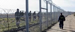 Geschlossen. Ein ungarischer Polizist beobachtet Flüchtlinge auf der anderen Seite des Zauns auf serbischem Territorium. 